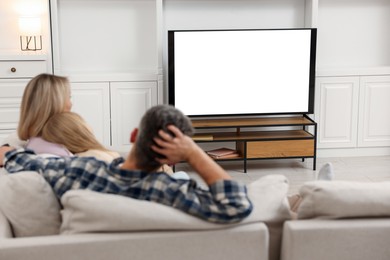 Photo of Family watching TV on sofa at home