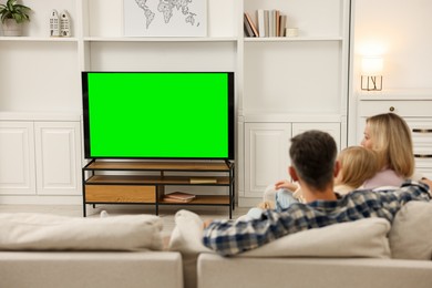 Photo of Family watching TV on sofa at home