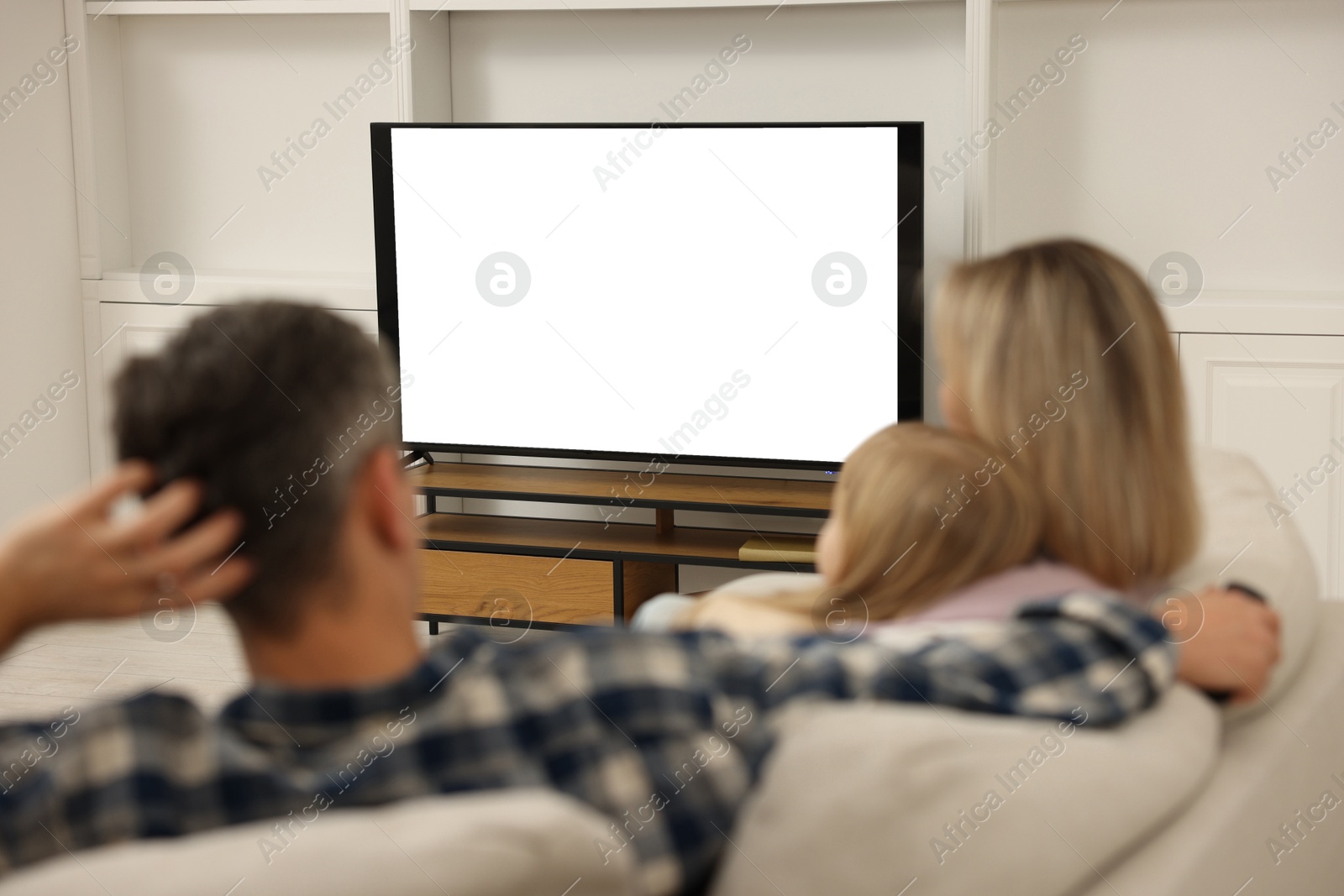 Photo of Family watching TV on sofa at home