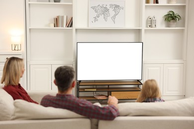 Family watching TV on sofa at home