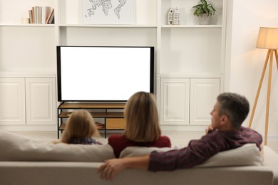 Photo of Family watching TV on sofa at home