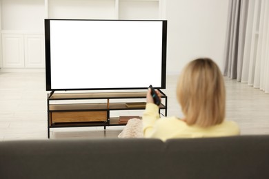 Photo of Woman watching TV on sofa at home, back view