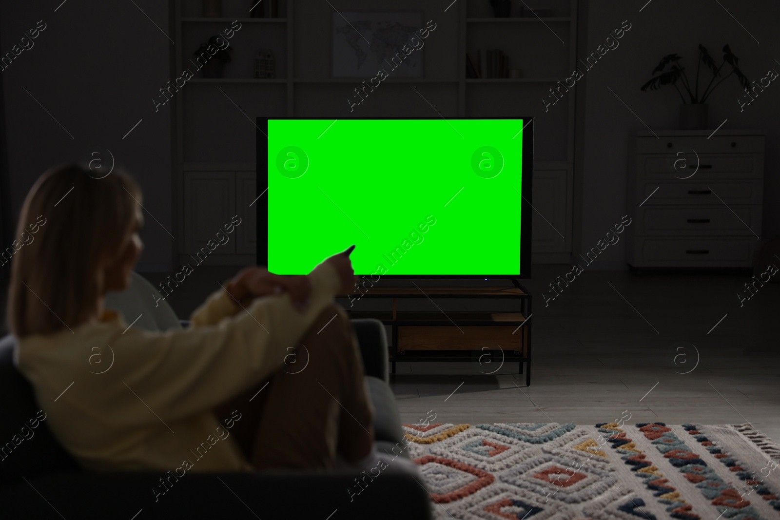 Photo of Woman watching TV on sofa at home in evening