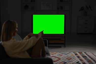 Photo of Woman watching TV on sofa at home in evening