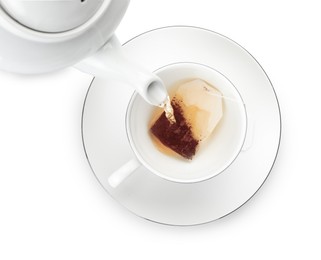 Photo of Pouring hot water into cup with tea bag on white background, top view