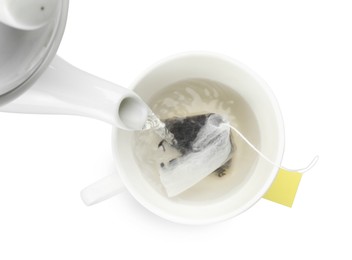 Photo of Pouring hot water into cup with tea bag on white background, top view