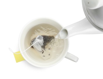 Photo of Pouring hot water into cup with tea bag on white background, top view