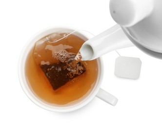 Photo of Pouring hot water into cup with tea bag on white background, top view