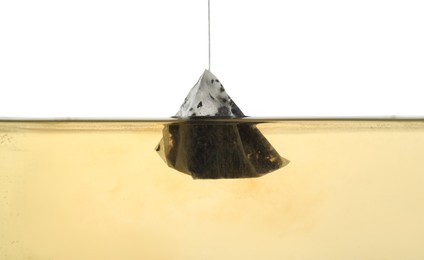 Photo of Putting tea bag into glass cup on white background, closeup