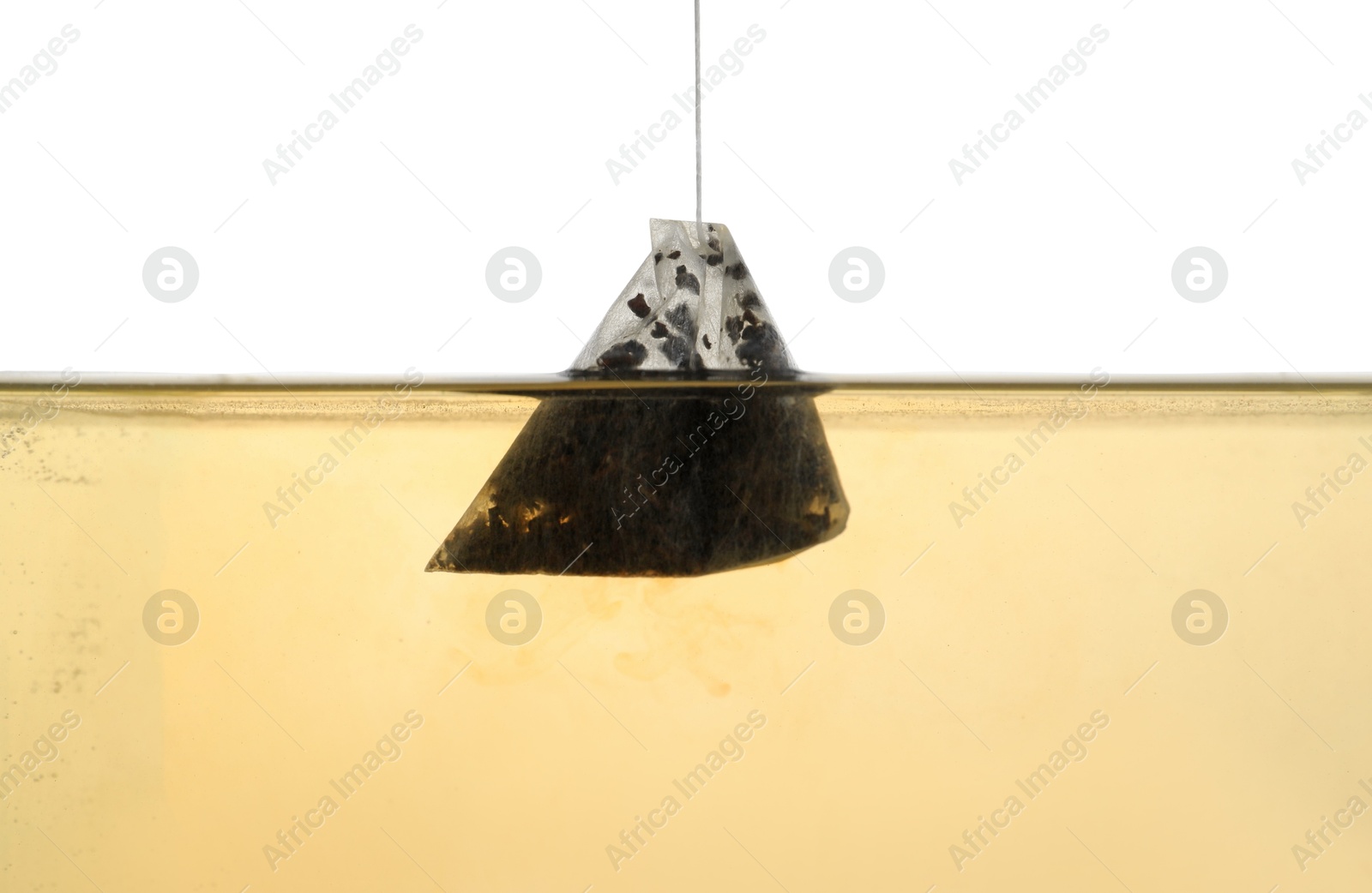 Photo of Putting tea bag into glass cup on white background, closeup