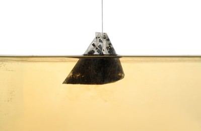 Photo of Putting tea bag into glass cup on white background, closeup