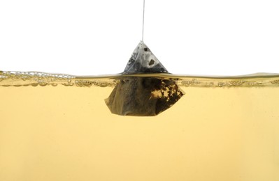 Photo of Putting tea bag into glass cup on white background, closeup