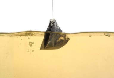 Photo of Putting tea bag into glass cup on white background, closeup