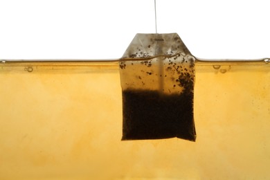 Photo of Putting tea bag into glass cup on white background, closeup