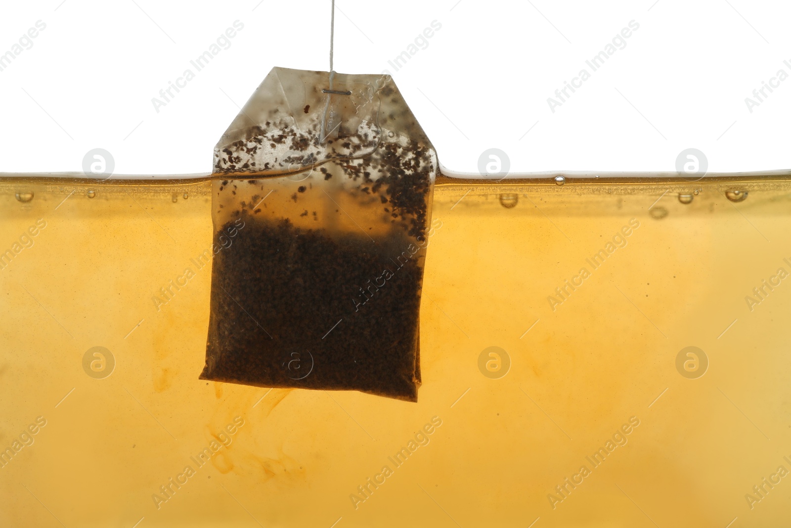 Photo of Putting tea bag into glass cup on white background, closeup