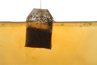 Photo of Putting tea bag into glass cup on white background, closeup