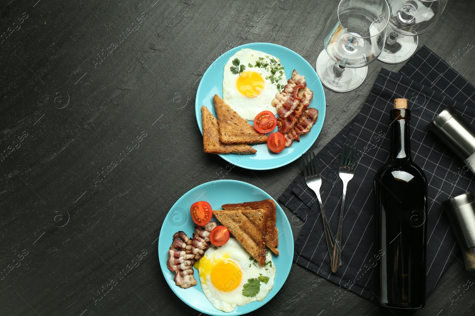 Photo of Tasty food and wine served for brunch on black table, flat lay. Space for text