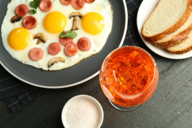 Photo of Tasty brunch. Delicious fried eggs with sausage and mushrooms served on black table, flat lay