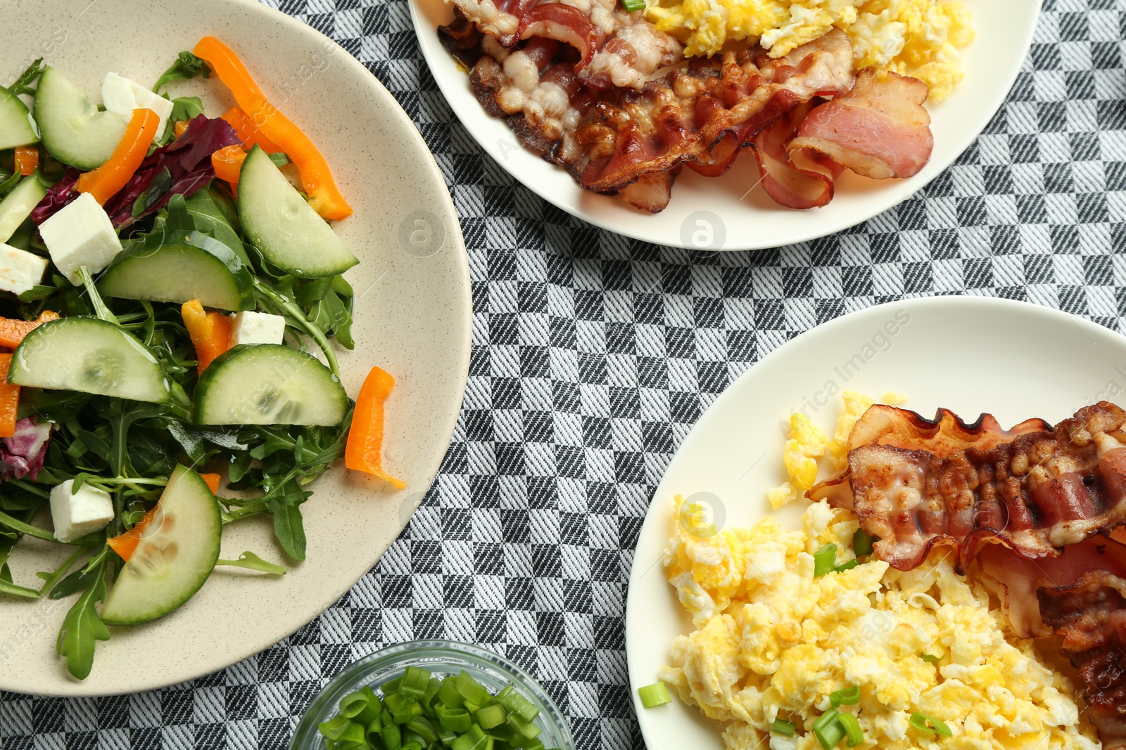 Photo of Tasty brunch. Delicious scrambled eggs, bacon and salad served on table, flat lay