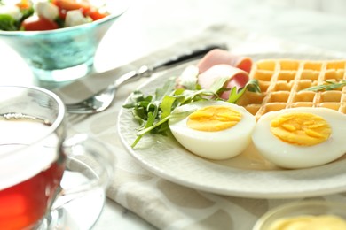 Photo of Tasty brunch. Boiled egg, Belgian waffle, arugula and ham on light table, closeup