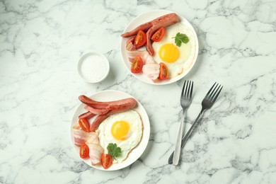 Photo of Tasty brunch. Fried eggs, sausage, bacon and tomatoes served on white marble table, flat lay