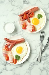 Photo of Tasty brunch. Fried eggs, sausage, bacon and tomatoes served on white marble table, flat lay