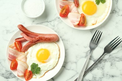 Photo of Tasty brunch. Fried eggs, sausage, bacon and tomatoes served on white marble table, flat lay