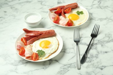 Photo of Tasty brunch. Fried eggs, sausage, bacon and tomatoes served on white marble table