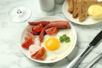 Photo of Tasty brunch. Fried egg, sausage, bacon and tomatoes on white marble table, closeup