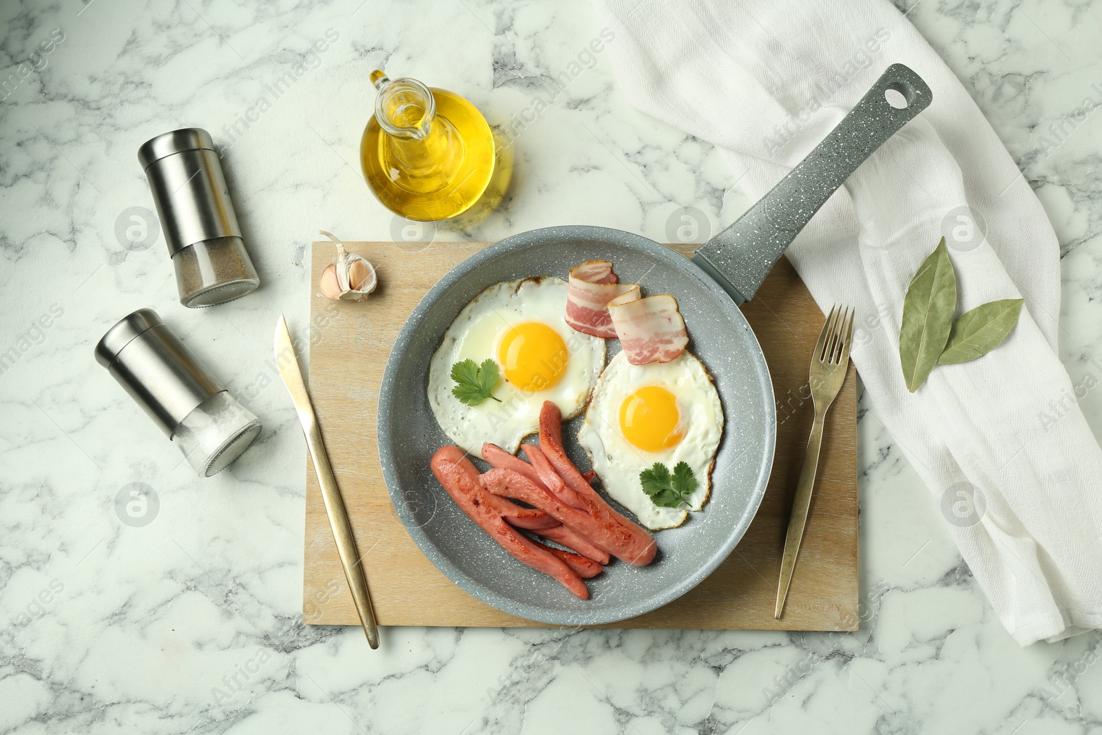 Photo of Tasty brunch. Fried eggs, sausages and bacon served on white marble table, flat lay