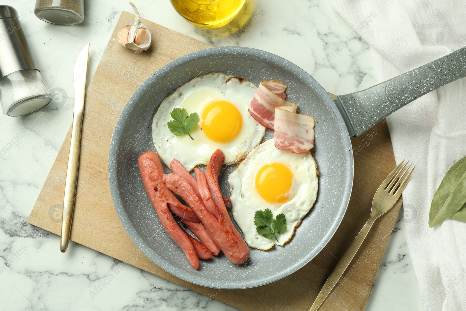 Photo of Tasty brunch. Fried eggs, sausages and bacon served on white marble table, flat lay