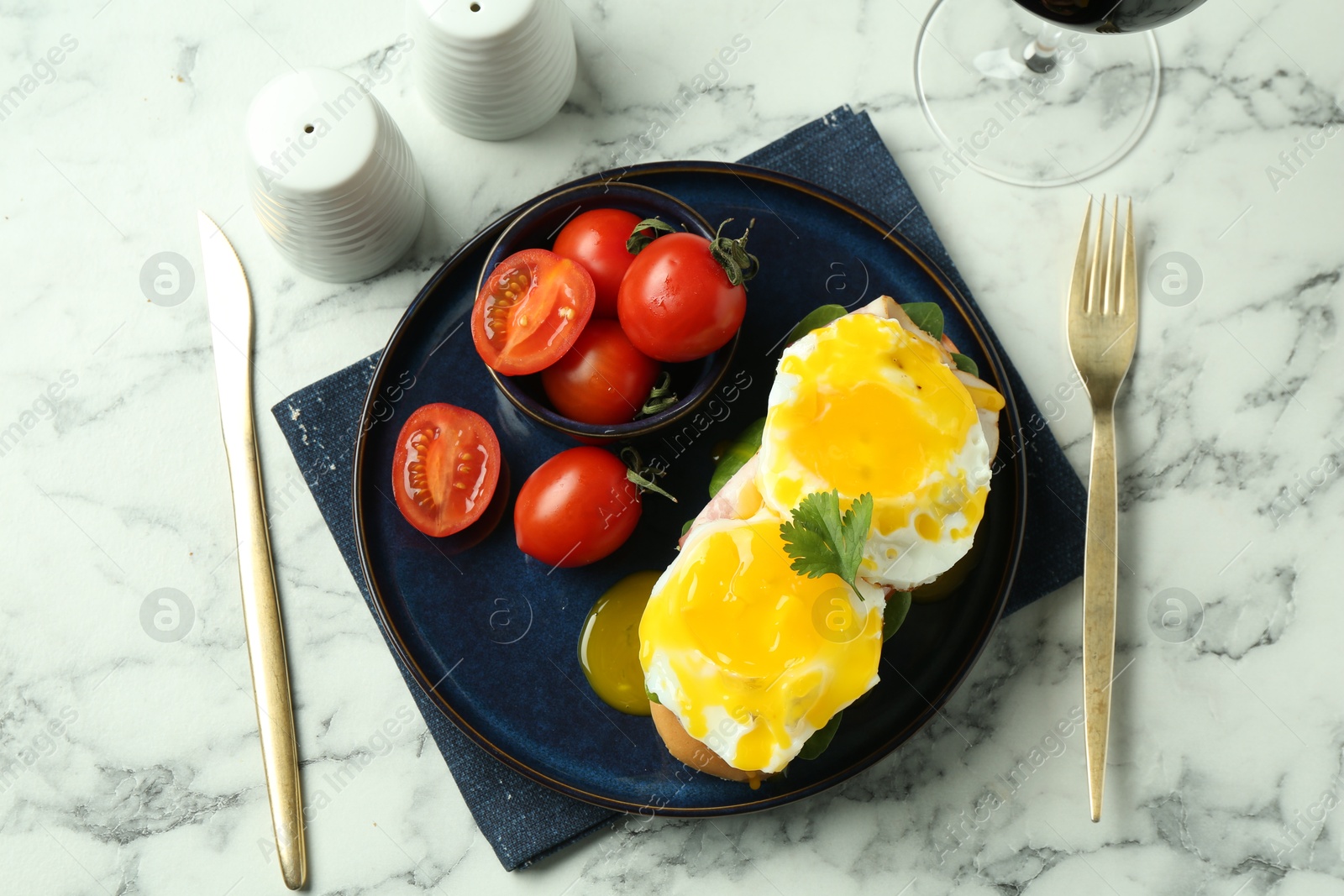 Photo of Tasty brunch. Poached eggs, bun and tomatoes served on white marble table, flat lay