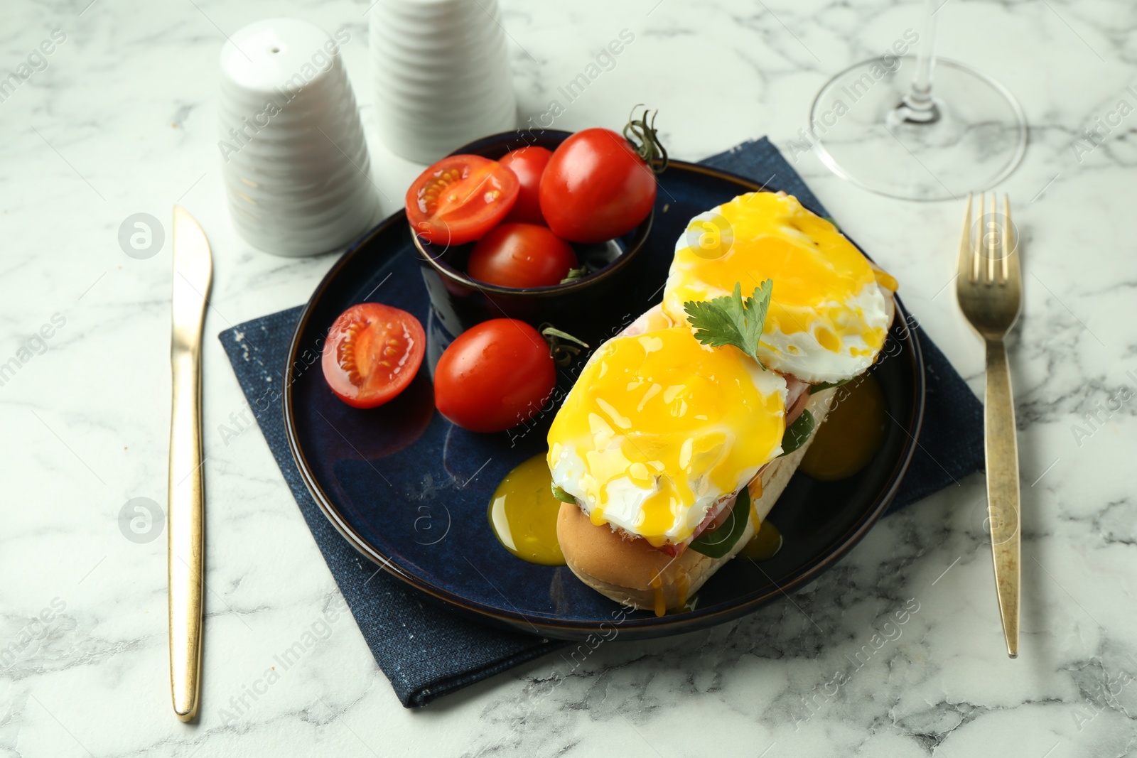 Photo of Tasty brunch. Poached eggs, bun and tomatoes served on white marble table