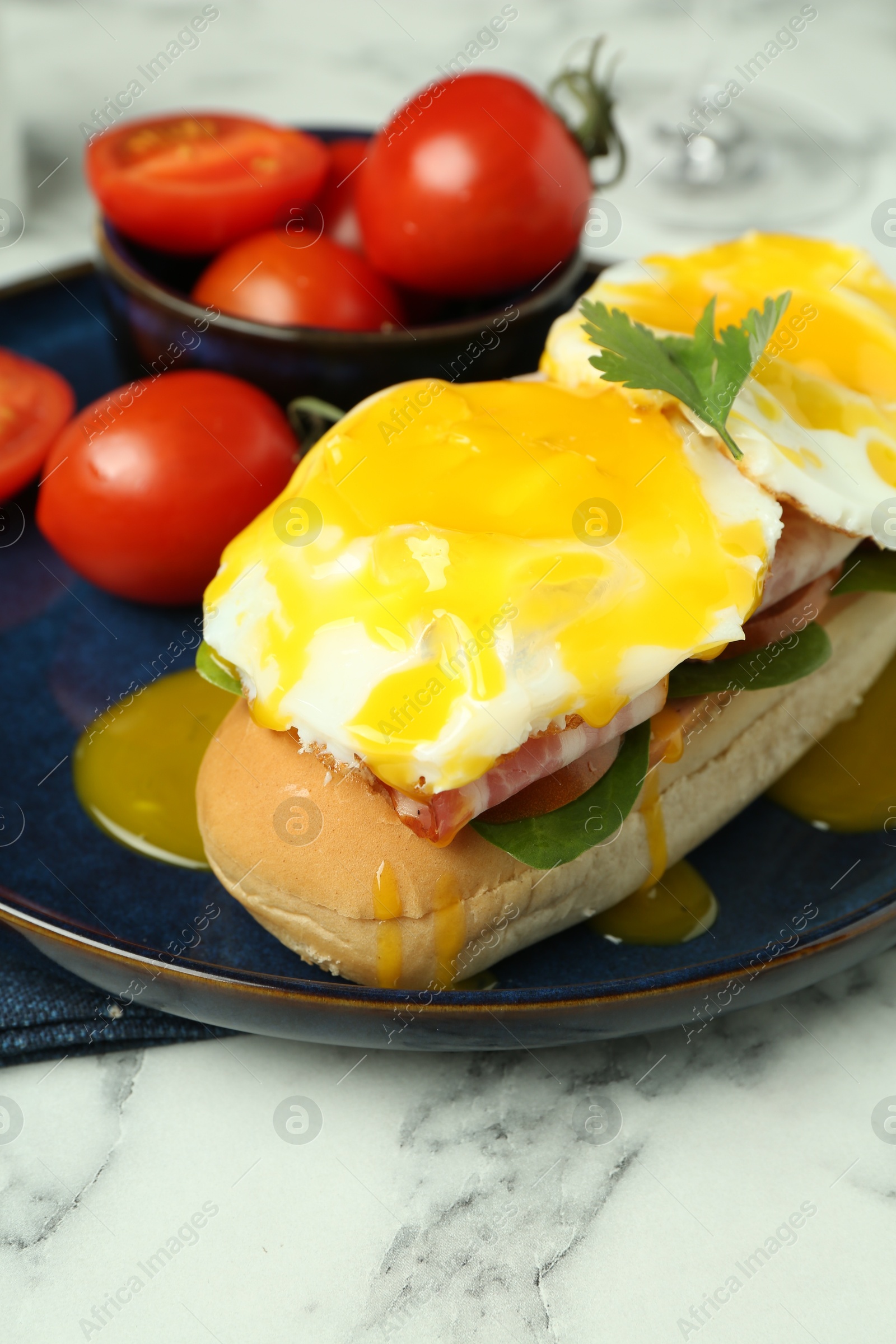 Photo of Tasty brunch. Poached eggs, bacon, bun and tomatoes on white marble table, closeup