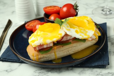 Photo of Tasty brunch. Poached eggs, bacon, bun and tomatoes on white marble table, closeup