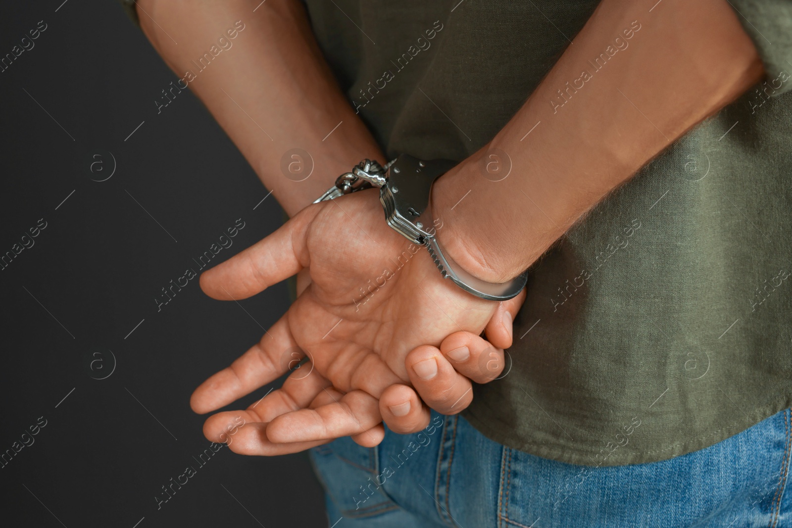 Photo of Man in metal handcuffs on black background, closeup