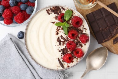 Photo of Tasty cooked semolina porridge with berries served on white tiled table, top view