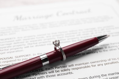 Photo of Marriage contract, pen and stylish ring on marriage contract, closeup