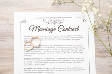 Photo of Marriage contract, flowers and golden rings on wooden table, top view