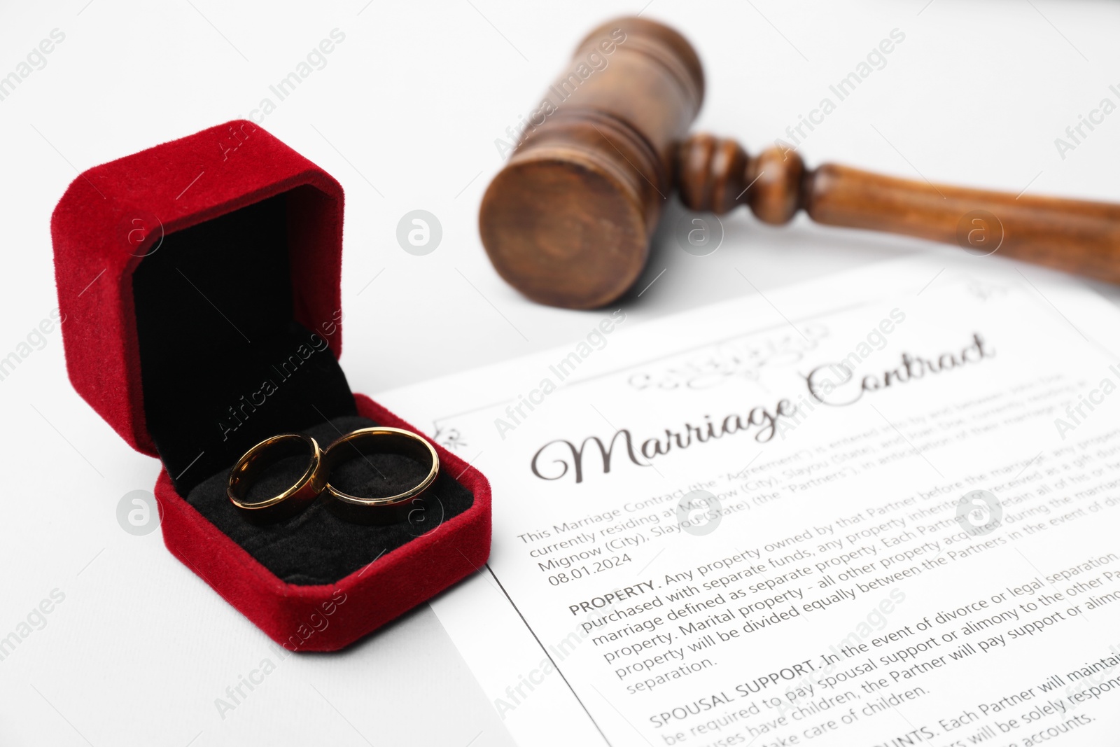 Photo of Marriage contract, gavel and golden rings on grey table, closeup