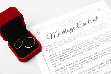 Photo of Marriage contract and golden rings on grey table, closeup