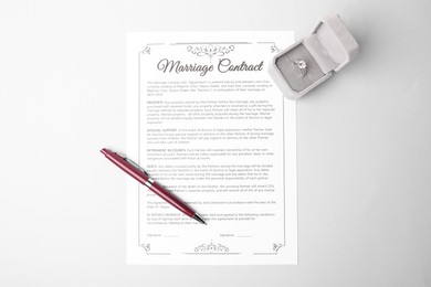 Photo of Marriage contract, pen and ring on grey table, top view