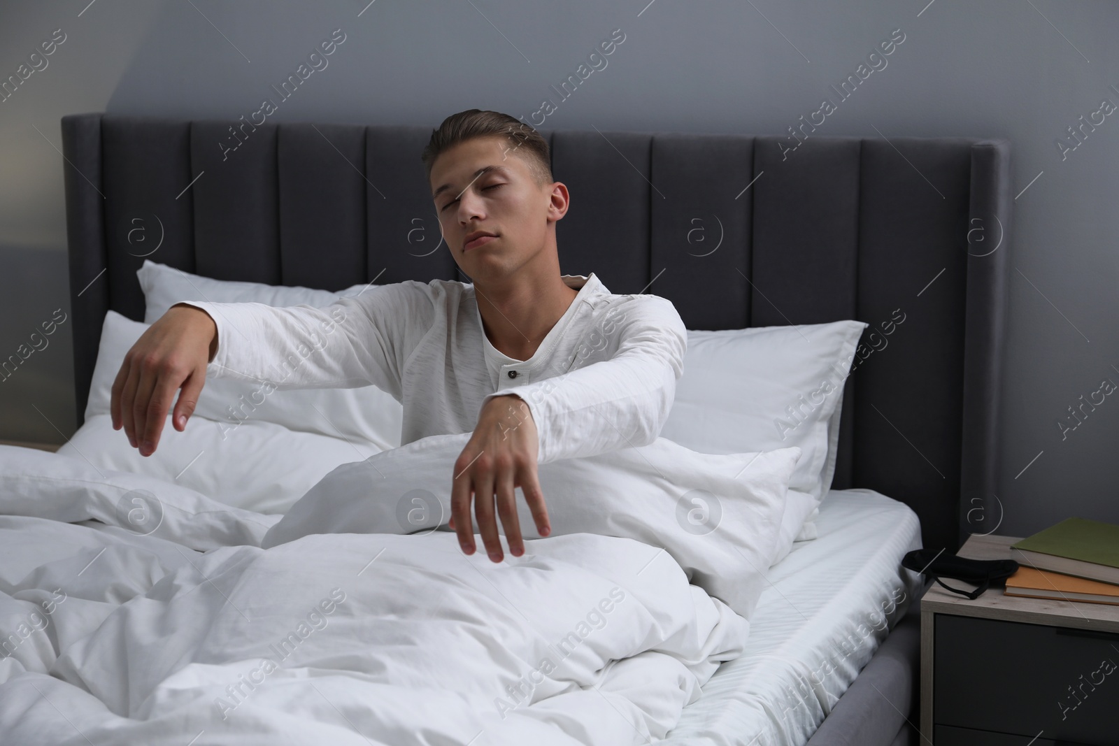 Photo of Young man suffering from sleepwalking on bed at home