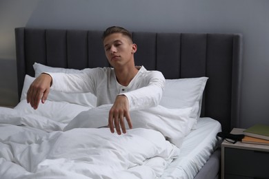 Photo of Young man suffering from sleepwalking on bed at home