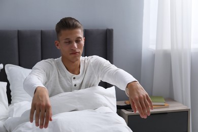 Young man suffering from sleepwalking on bed at home