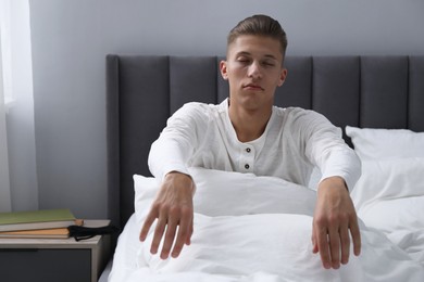 Photo of Young man suffering from sleepwalking on bed at home