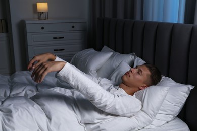 Photo of Young man suffering from sleepwalking on bed at home