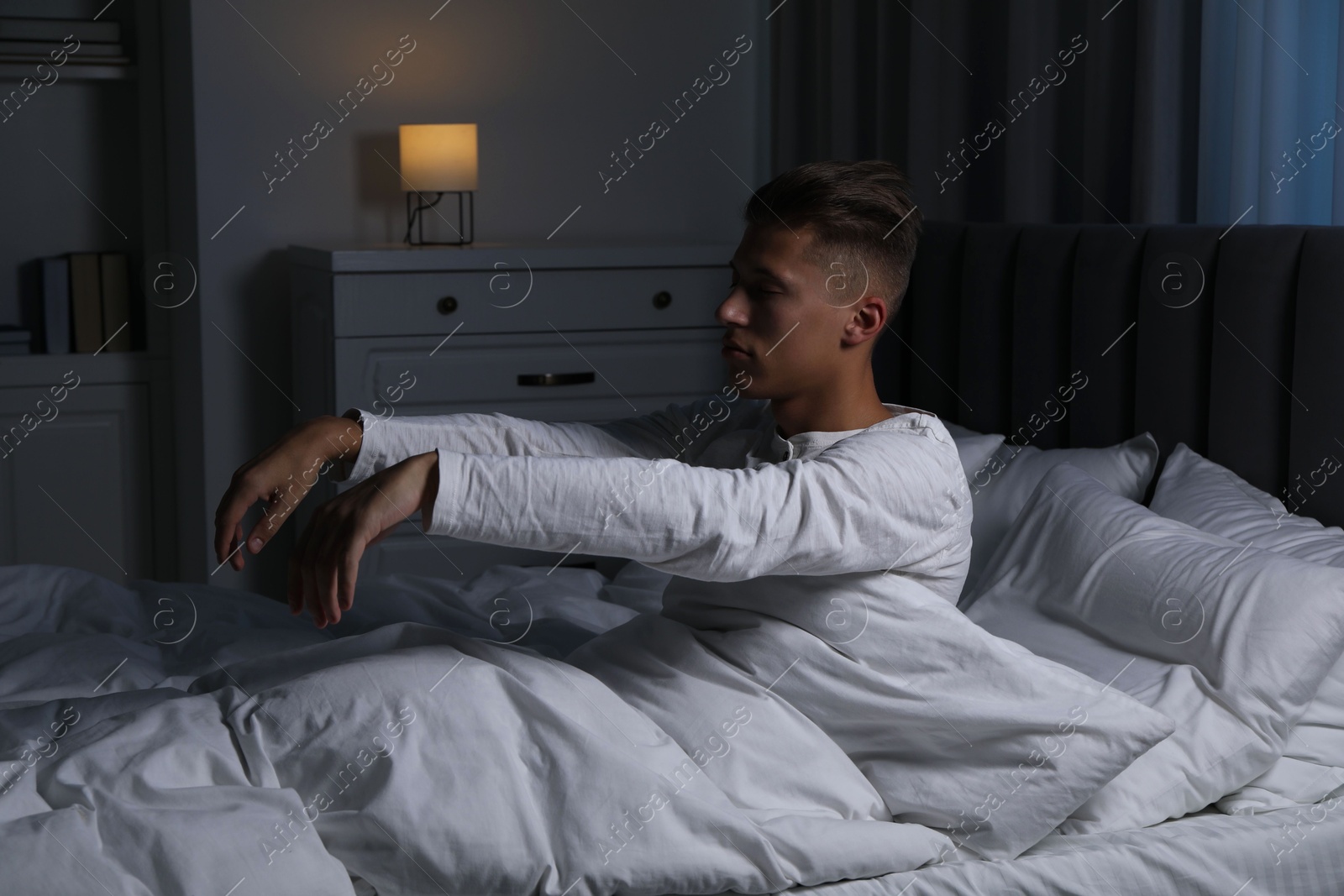 Photo of Young man suffering from sleepwalking on bed at home