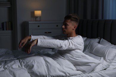 Young man suffering from sleepwalking on bed at home