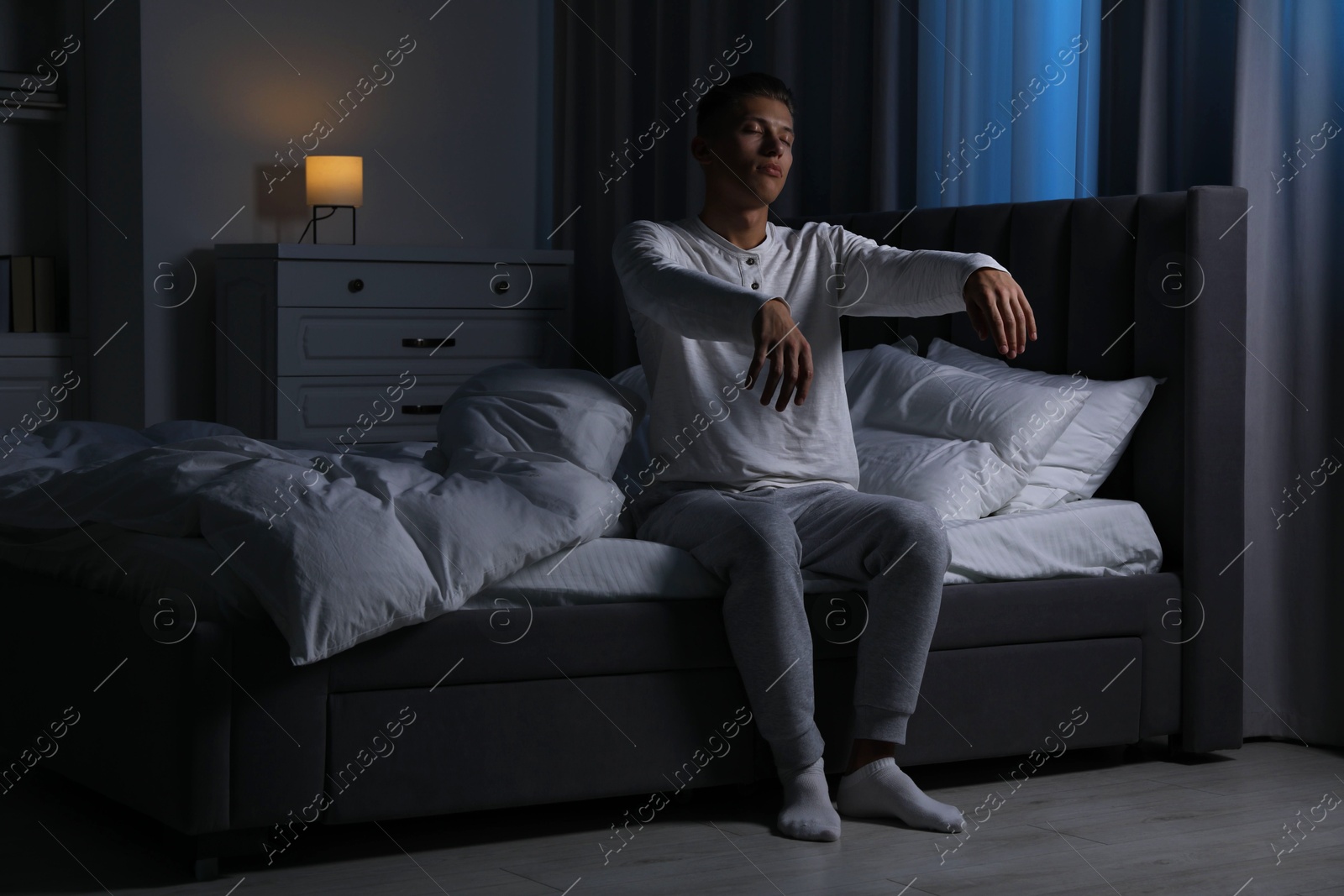 Photo of Young man suffering from sleepwalking on bed at home